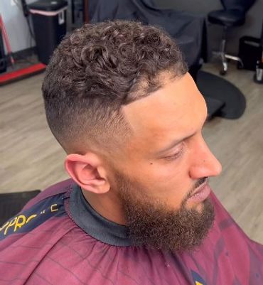 Man with a fresh haircut featuring a fade and curly top.