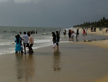 People enjoying a beach under cloudy skies.