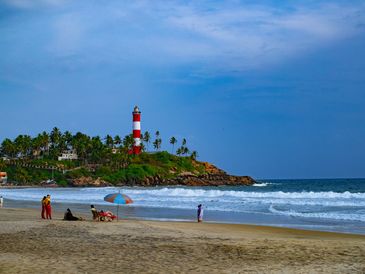 Beach view with a lighthouse and people relaxing.