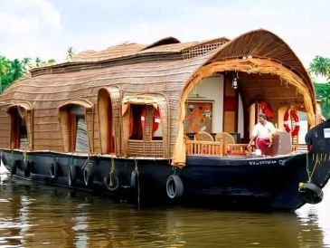Traditional houseboat with thatched roof cruising on water.