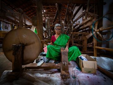 Woman working on a traditional spinning wheel.