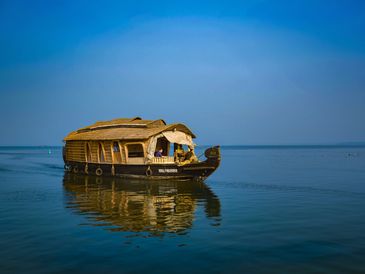 Traditional houseboat on calm water under clear blue sky.