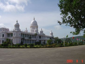 A grand white palace with domes and greenery.