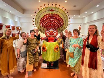 Group of women posing around a traditional dancer statue.