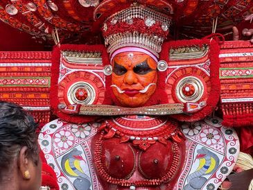 Colorful traditional Theyyam performer with elaborate costume.