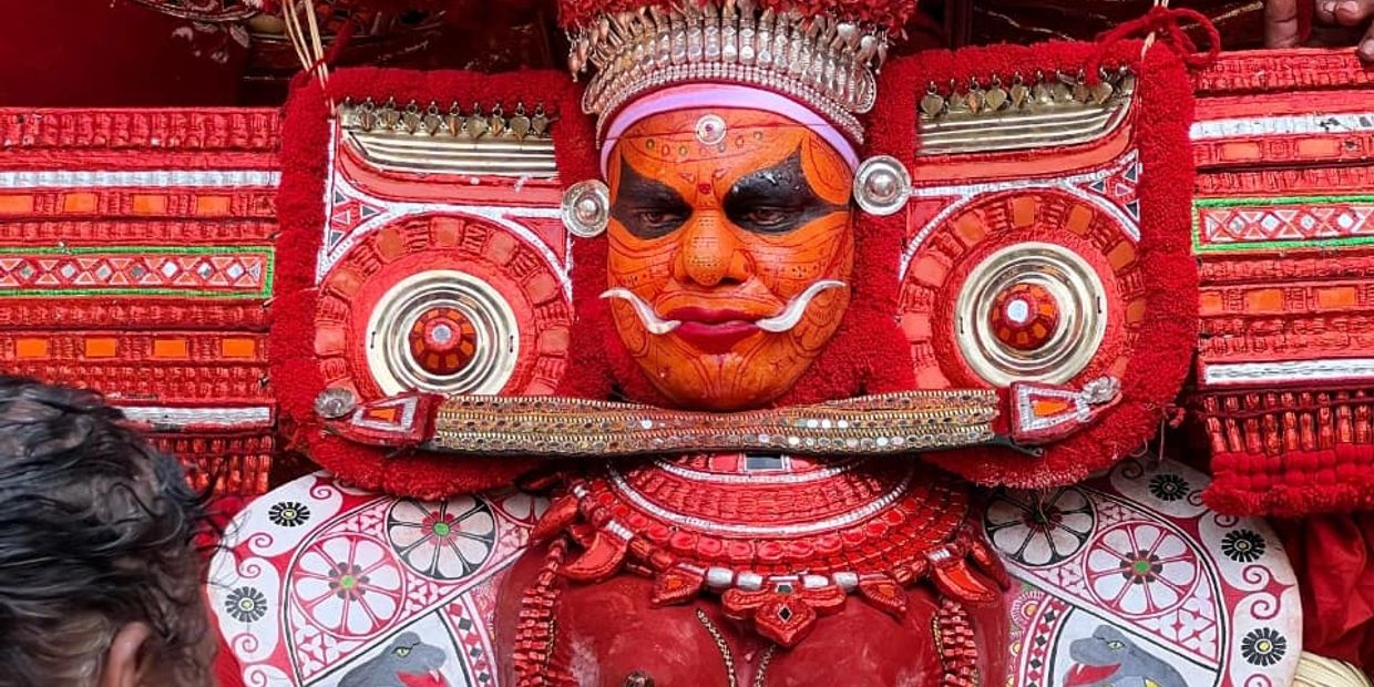 Traditional red and orange ritualistic face painting and attire.
