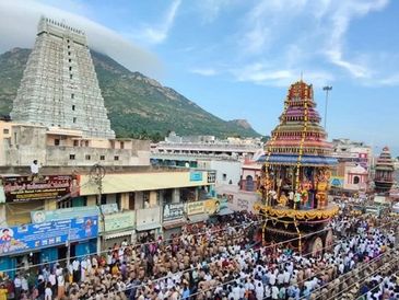 A large procession with a temple tower in the background.