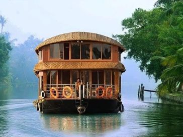 A houseboat on a calm river surrounded by greenery.