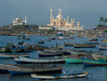 Boats docked near a distant mosque on the coast.