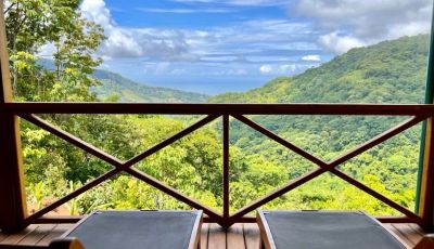 Scenic balcony view of lush green hills and blue sky.
