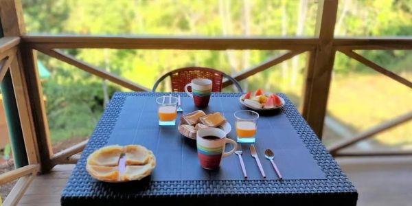 Breakfast set on a table on a balcony with nature view.