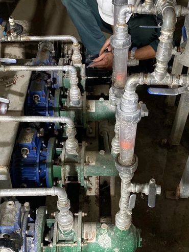 Technician working on industrial piping and pump system.