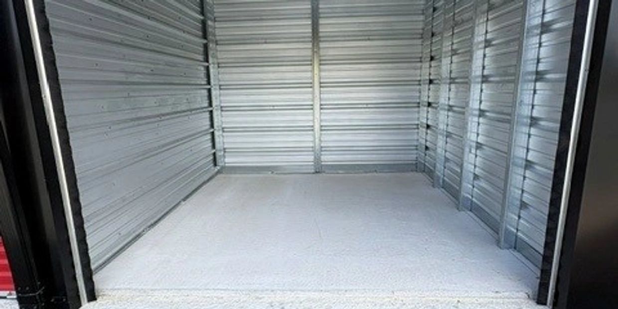 Empty metal storage unit with a concrete floor.