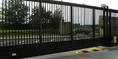 A tall black metal security gate blocks a driveway.