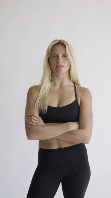 Confident woman in black workout clothes with arms crossed.