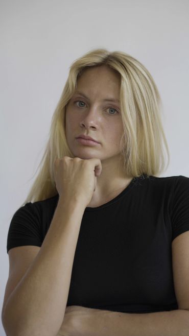 Thoughtful young woman with blonde hair in a black shirt.
