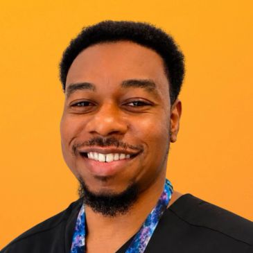 Man smiling against a yellow background.