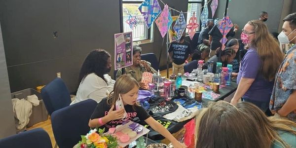 People engaging at a colorful indoor market booth with handmade crafts and decorations.