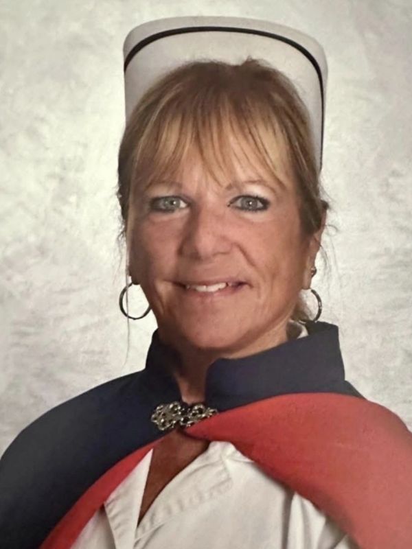Woman in vintage nurse uniform with white hat and red cape.