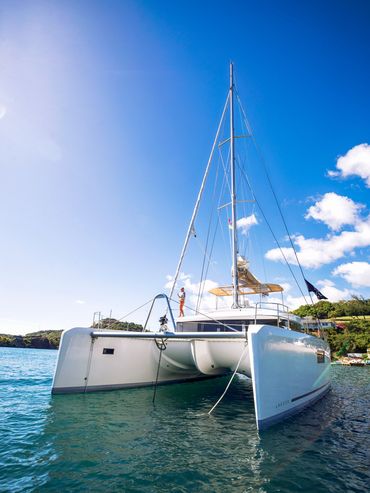 A white catamaran yacht anchored in clear blue water on a sunny day.