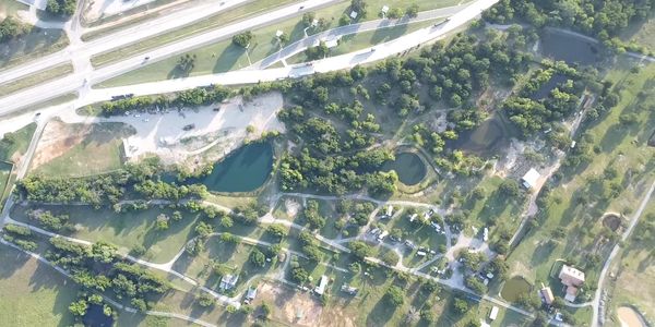 Aerial view of a green area with ponds and roads.