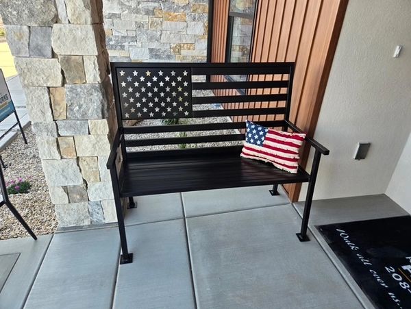 Black metal bench with an American flag design and a matching flag pillow.