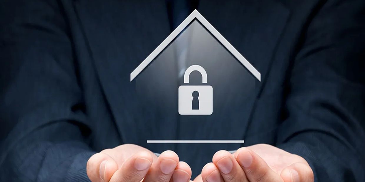 Hands protect a digital house with a lock symbol, representing security.