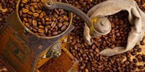 Vintage coffee grinder with roasted coffee beans scattered around.
