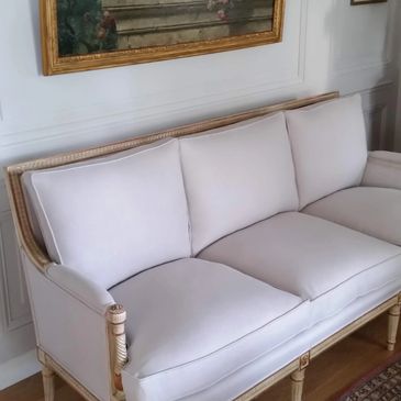 Elegant white upholstered sofa with wooden frame and cushions.