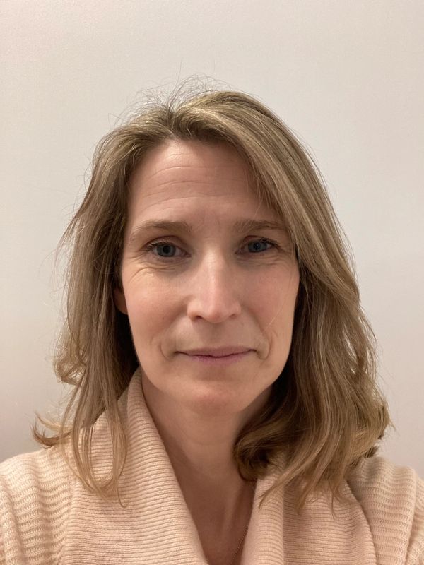 Close-up of a woman with light brown hair and a beige sweater.