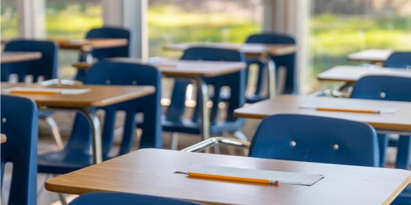 Empty classroom desks with pencils and rulers ready for students.