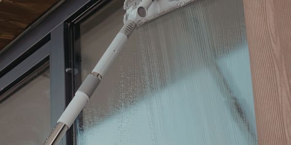 Person cleaning a glass window with a mop.