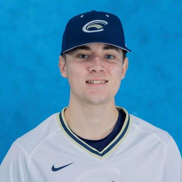 Young baseball player in uniform against blue background.