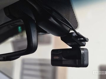 A dashcam mounted on a car's rearview mirror.
