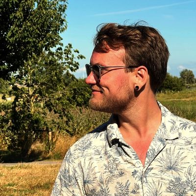 Young man with sunglasses in a tropical shirt outdoors on a sunny day.