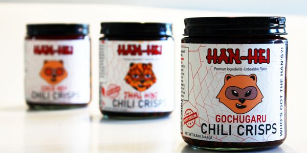 Three jars of Han-Hei chili crisps with animal logos on the labels.