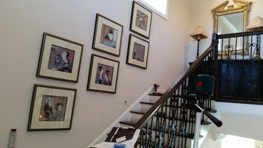 Laser level tool used for hanging framed artwork on stairway wall.