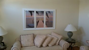 Cozy living room with beige couch and serene beach-themed wall art.