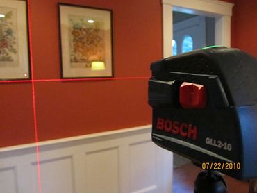Bosch GLL 2-10 laser level projecting red cross lines on a wall.