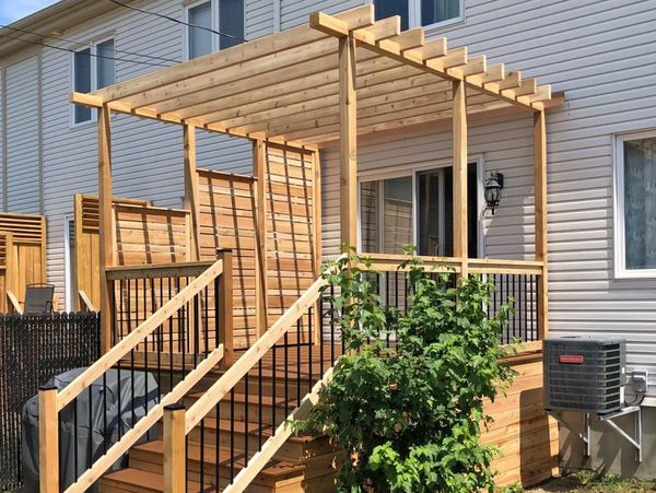 Wooden pergola and staircase attached to a house exterior.