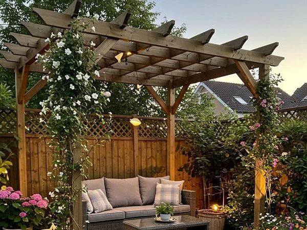 Cozy backyard seating area under a wooden pergola with climbing plants and soft lighting.