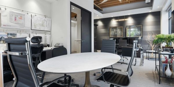 Modern office space with a round white table and black chairs.