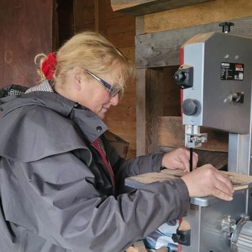 Woman using a bandsaw machine in a workshop.