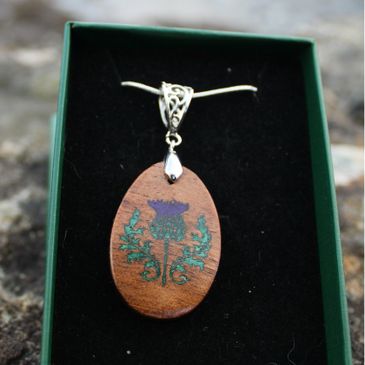 Wooden pendant with floral design in a green box.