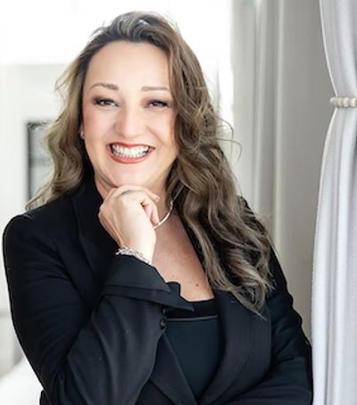 Smiling woman in black blazer indoors.