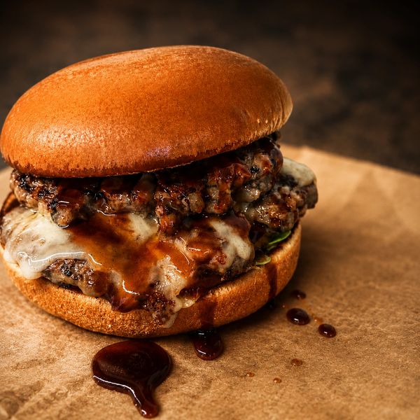 Juicy cheeseburger with sauce on a brown paper.