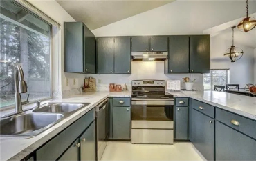 Modern kitchen with dark blue cabinets and stainless steel appliances.