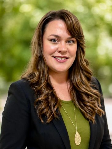 Smiling woman in professional attire with wavy hair.