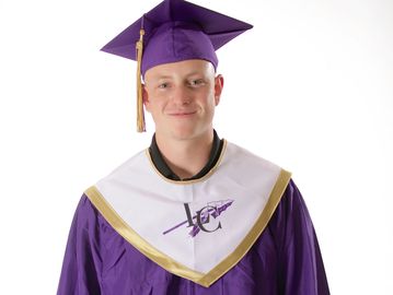 Young graduate in purple cap and gown with white and gold stole.