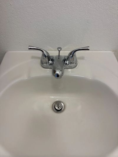 A clean, white bathroom sink with chrome faucet handles.